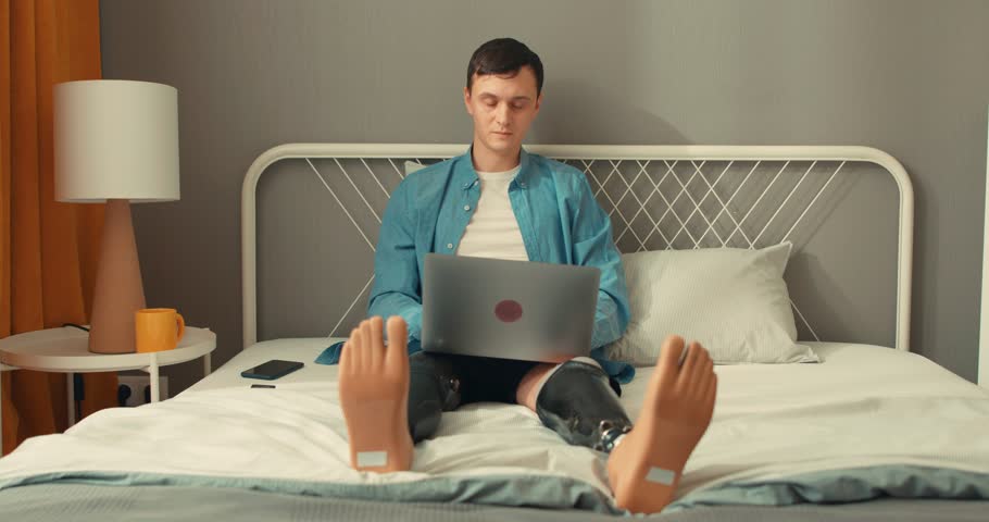 Disabled pale week man spending free time, using laptop, smartphone, watching TV, turning on TV with control panel. controller, leisure free spare time lifestyle interests | Shutterstock HD Video #1104344161