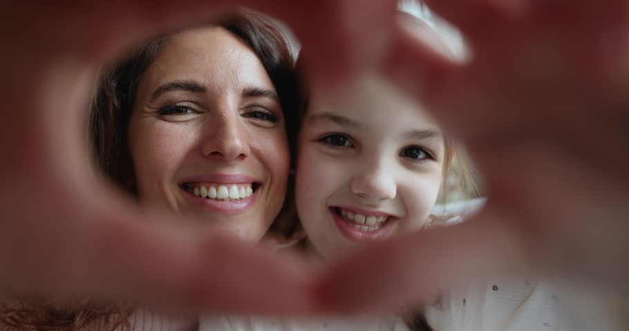 Portrait of young beautiful Hispanic woman and adorable Caucasian daughter making heart shape hand gesture to camera showing family love and ties, close up view. Happy motherhood, custody and adoption Royalty-Free Stock Footage #1104348983