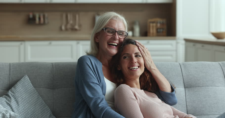 Older woman hugs her grown up daughter enjoy moment of caress and tenderness seated together ion cozy sofa in cozy living room. Multi-generational family ties and bonding, motherhood, understanding Royalty-Free Stock Footage #1104349077