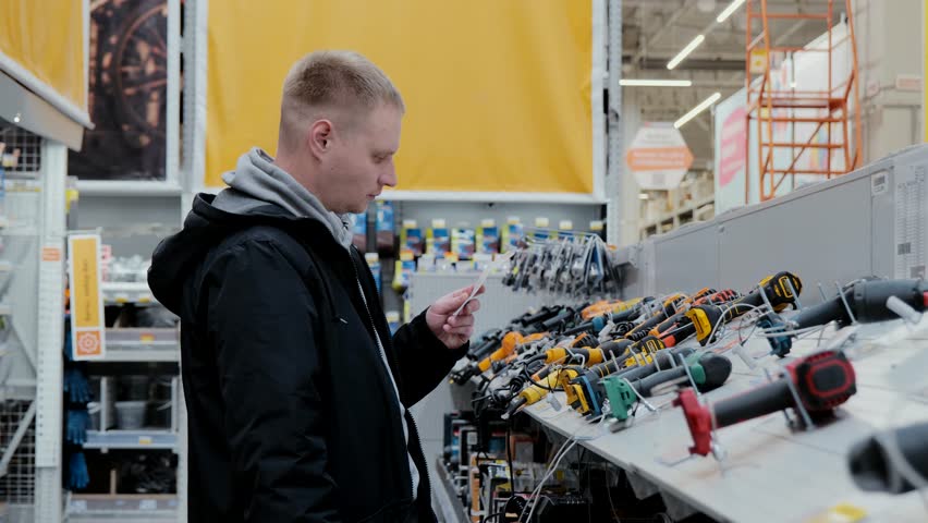 Buying a screwdriver at a hardware store. A man in a hardware store buys a power tool. Cordless power tools. Construction equipment supermarket | Shutterstock HD Video #1104349669