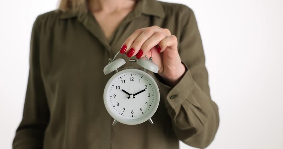 Woman holds white alarm clock and red umbrella on white | Shutterstock HD Video #1104349989