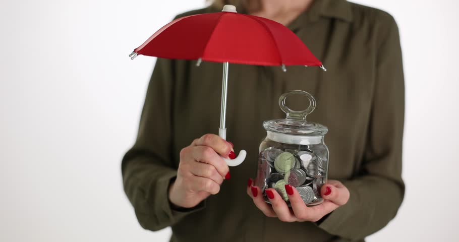 Woman covers coins jar with red umbrella on white background | Shutterstock HD Video #1104350003