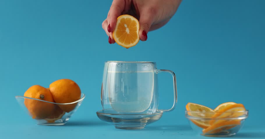 Female hand squeezing fresh lemon dripping into water | Shutterstock HD Video #1104350047