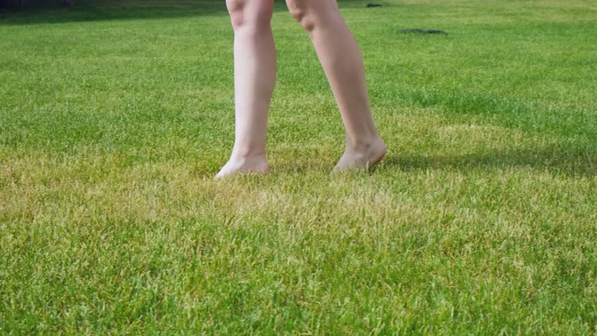 Feet of a young girl walking barefoot on yellow-green grass on a spring or summer sunny morning. Slow motion. | Shutterstock HD Video #1104353299