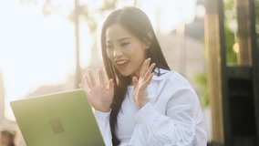 Portrait of beautiful asian woman with long dark hair having video call conference meeting by laptop computer at park Smiling student talking on working or personal conversation outdoors