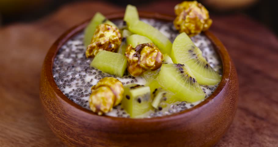 Fresh yogurt with kiwi flavor and with pieces of fruit, chia seeds and popcorn, delicious fresh yogurt with the addition of pieces of ripe yellow kiwi with chia and popcorn | Shutterstock HD Video #1104356695