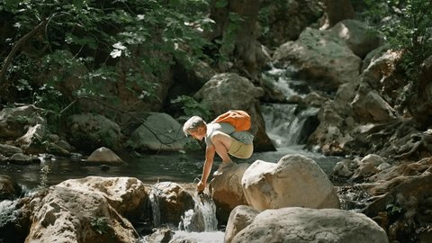 slow motion man hiker taking fresh cold clean water in palms from mountain river and drinks during hike in jungle. clean and safety environment concept. water resources, earth, environment Arkivvideo