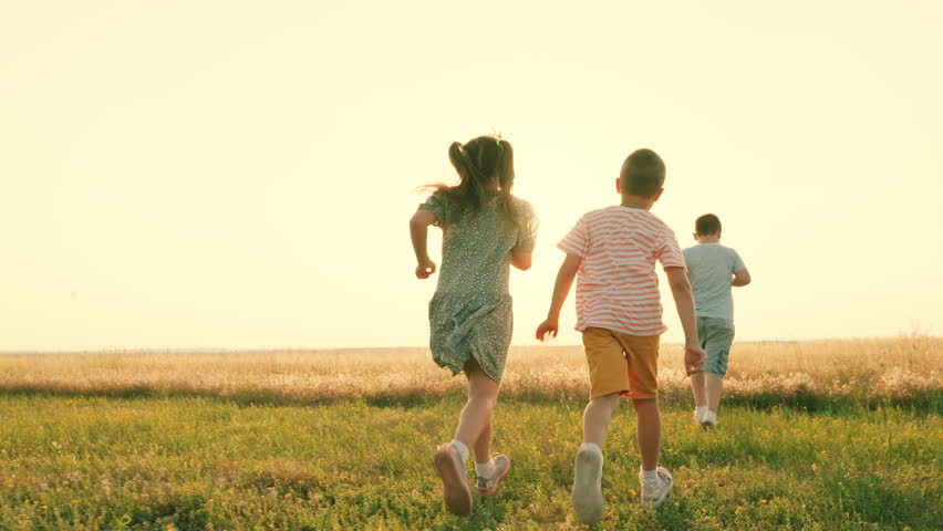 Child run on grass, sunset, sport. Happy boy, girl run in field, playing in nature. Teenagers play running in sun, kids play in park, friends run in summer. Family, weekend outdoors. Holiday childhood