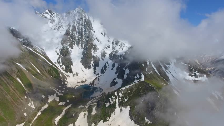 Aerial view of high altitude alpine lake in snowy mountain bowl.