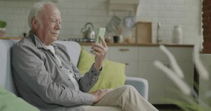 Portrait of retired man making video call talking waving hand enjoying conversation indoors at home. Internet connection and retirement concept.