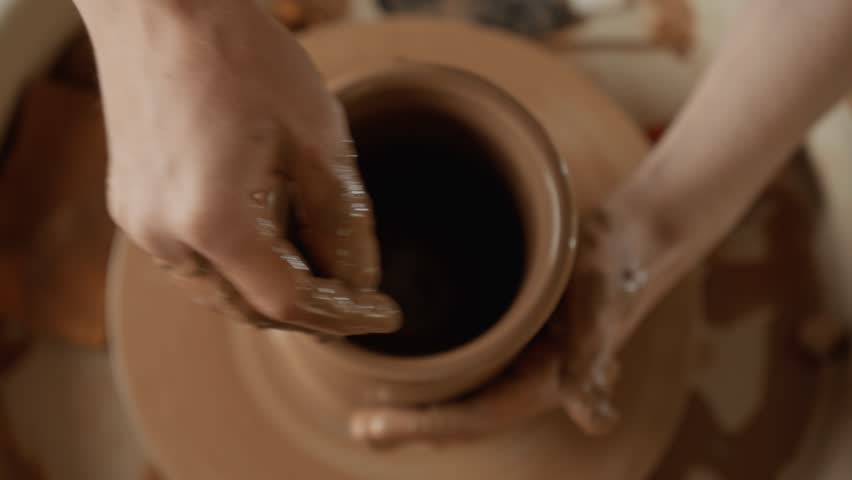 Working with clay. Top view. Man potter making ceramic vase on potters wheel from clay. Close-up in 4K, UHD