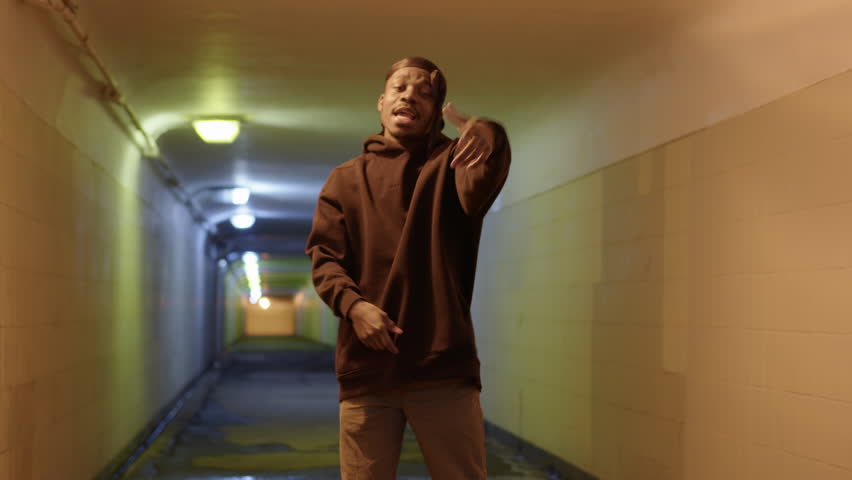 Black rap performer enjoys recording rap music video in illuminated underground