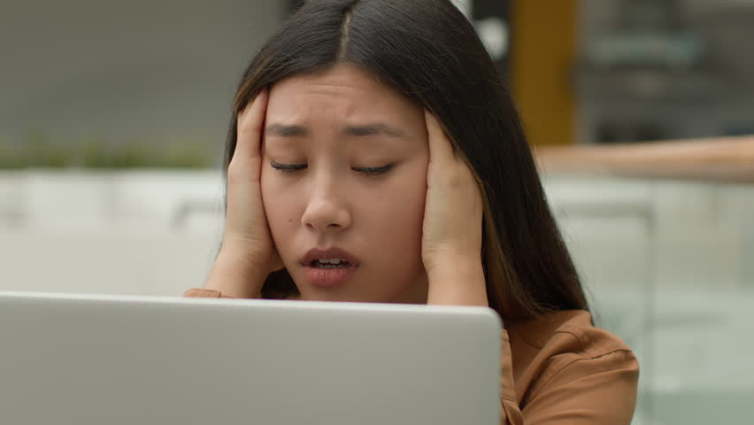 Exhausted overworked Asian woman girl student studying online work on laptop in office hold head headache tired chinese korean female employee businesswoman upset job failure despair fatigue burnout Royalty-Free Stock Footage #1104363981