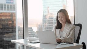 Busy Asian business woman using laptop in company office. Young female digital finance professional worker using computer doing corporate analysis online management sitting at desk, city window view. - Powered by Shutterstock - Get 15% off with code: PIKWIZARD15