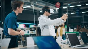 Young Man Having a Conversation with a Salesperson in a Electronics Store while Trying Out a Virtual Reality Device. Customer Wishes to Buy a VR Set. Shopper Explores Latest Options with Expert Advice - Powered by Shutterstock - Get 15% off with code: PIKWIZARD15