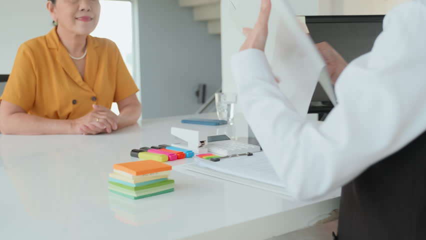 Waist up of old Asian woman signing insurance policy while having office meeting with agent helping her Royalty-Free Stock Footage #1104370827