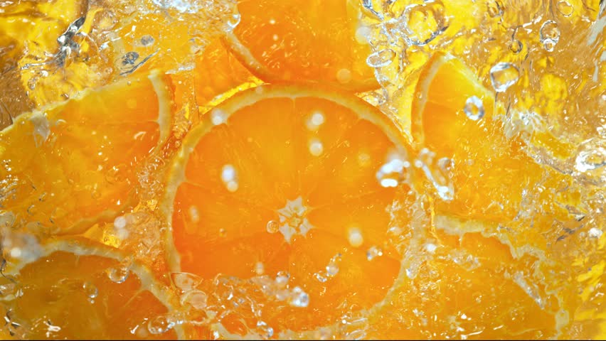 Super Slow Motion Shot of Fresh Orange Slices Falling into Water Whirl at 1000 fps.