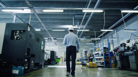 Engineer in Hard Hat is Walking Through Factory. Back View. Shot on RED Cinema Camera in 4K (UHD).