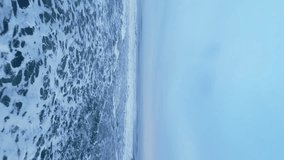 Vertical video: Drone shot of nordic ocean shore with natural black sand beach and icelandic landscape, snowy mountains and fields. Majestic altantic coastline on roadside, arctic panoramic view. 60 - Powered by Shutterstock - Get 15% off with code: PIKWIZARD15