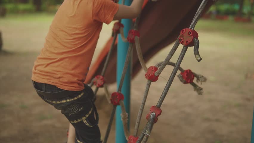 A cheerful and determined young child fearlessly climbs the rope in the lively kids