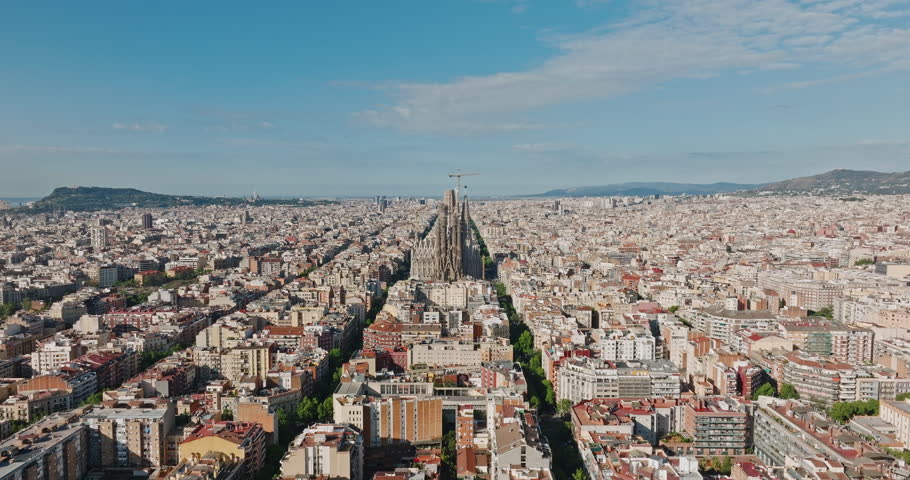 Sagrada Familia Barcelona, Spain Eixample residential area. Architectural heritage of country in summer on sunny day blue sky aerial view slide drone forward. Go Everywhere Travel. UNESCO. Tourism