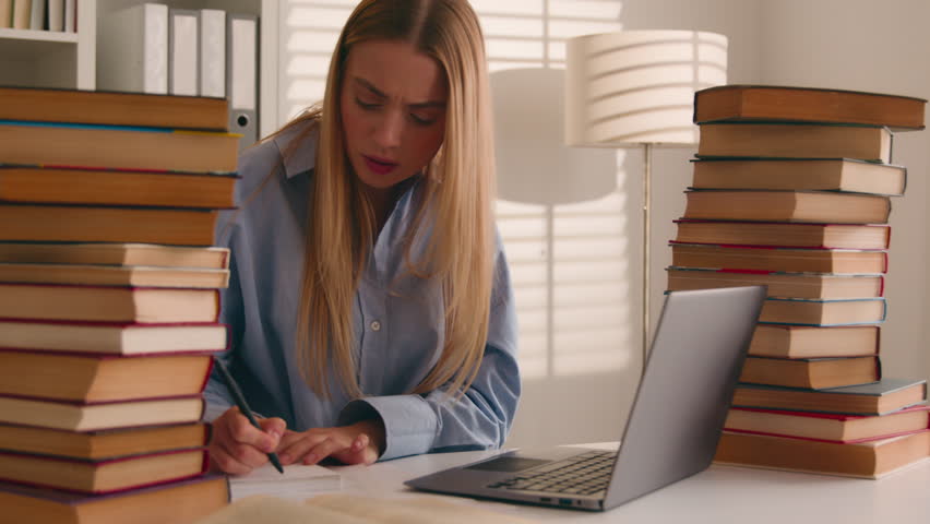 Stressed busy annoyed Caucasian student girl high school pupil woman stressful leaner studying with laptop and books homework prep to exams learning online search information e-learning difficulties Royalty-Free Stock Footage #1104384181