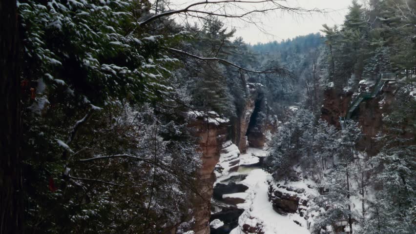 River Flowing Through Sandstone Gorge And Snowy Terrain At Ausable Chasm In New York During Winter. high angle