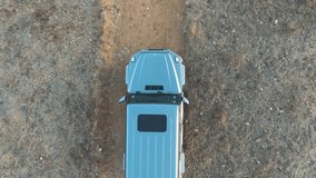 Aerial top down view of an off road vehicle driving in a sandy unpaved road