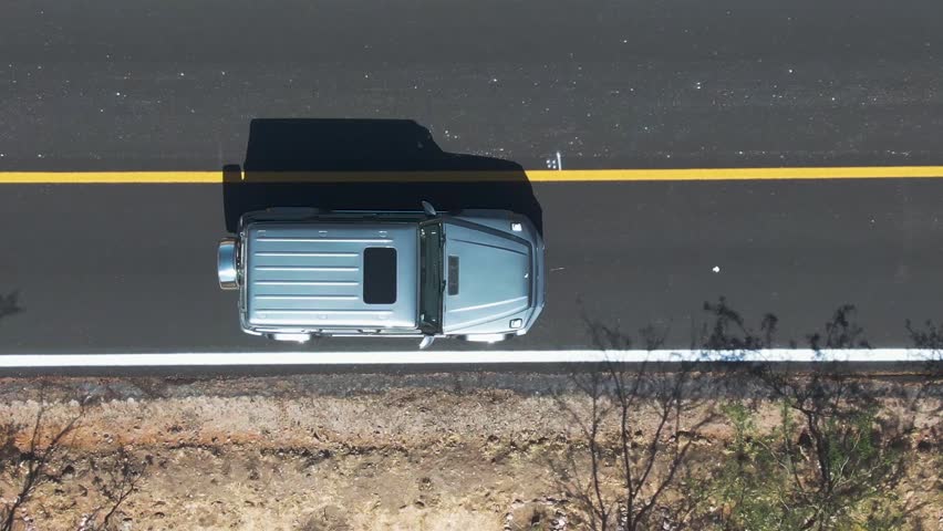 4X4 Mercedes-Benz car driving on a road in dry landscape. Aerial top down view