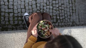 overhead view of an unrecognizable woman stirring a salad to eat on the street in her spare time.