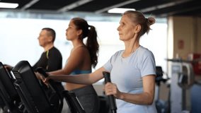Concentrated elderly woman working out on elliptical machine in gym. Concept of healthy lifestyle of older generation - Powered by Shutterstock - Get 15% off with code: PIKWIZARD15