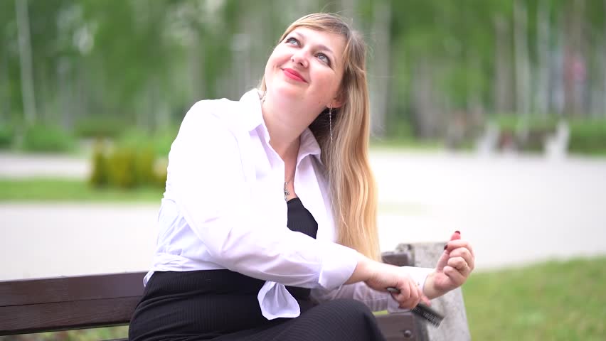 Girl in the park on a bench. Makeup, maquillage. Beautiful blonde. Young woman in a white shirt with a mirror. Childfree woman. Business lady. Relax. Plus size model.                               