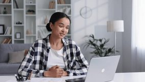 Attractive young woman works from home, has a video call with colleagues, shows graphs. Attractive young African American female student studying at home, giving a work presentation.
