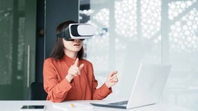 Asian successful businesswoman using VR glasses for video call and chatting online in virtual reality simulator while sitting at workplace in modern office Online conference with colleagues remotely - Powered by Shutterstock - Get 15% off with code: PIKWIZARD15