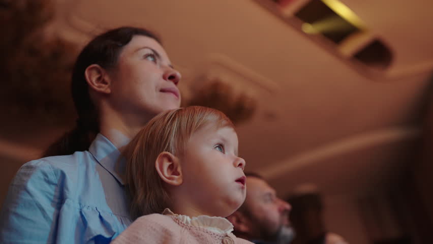 Cute little girl with her mother watching a performance in the theater or movie in the cinema. Leisure entertainment for family with kids. Cultural event for children.
 Royalty-Free Stock Footage #1104408701
