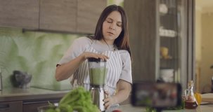 Cheerful blogger girl talks about healthy lifestyle and shoots video recipe. Girl looks and speaks to smartphone camera. Slow motion