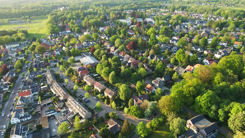 Aerial overview of a beautiful green suburban neighborhood. A few cars a driving on a road