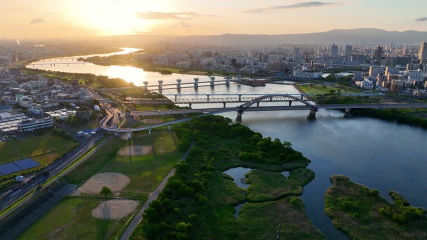 flying above Osaka, Japan at sunrise with Yodogawa river and railway bridges, tourism in Japan, Japanese metropolis in the morning, travel in Osaka city. High quality 4k footage