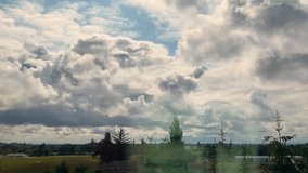 Timelapse of dynamic clouds moving over rural land with pine trees