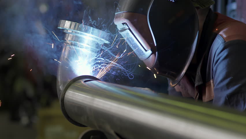 Welding work close-up. Welder worker weld pipe in protective helmet. Sparks fly out, Welding shop at Construction of Oil, Natural Gas and Fuels Transport Pipeline. Industrial Manufacturing Factory Royalty-Free Stock Footage #1104419921