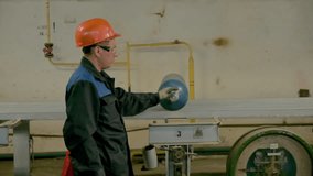 Worker in uniform at old factory. Clip. Worker easily moves gas cylinder at factory. Worker in uniform at industrial plant with old equipment