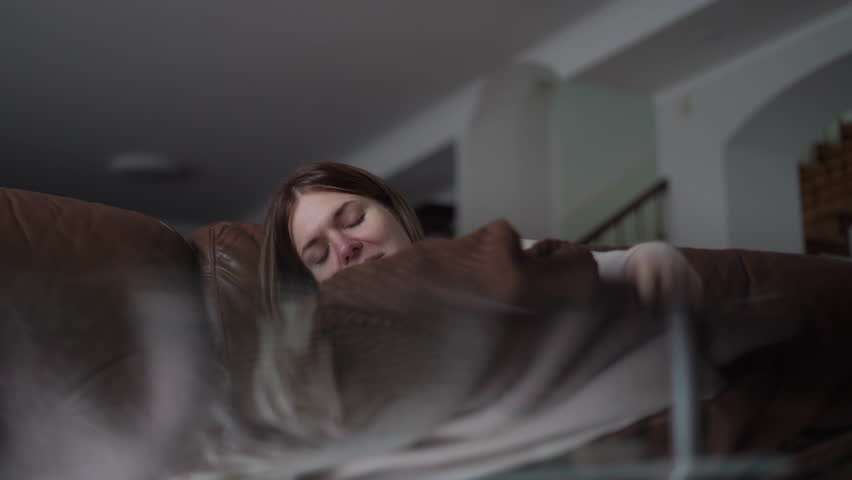 Shooting through glass of happy satisfied young woman taking a nap on couch as live camera moves up. Relaxed Caucasian millennial lady falling asleep on sofa in living room at home | Shutterstock HD Video #1104423265