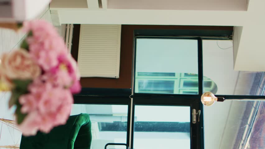 Vertical video Hotel bellhop carrying lugagge in lobby, providing luxury service to hotel guests arriving on tropical summer vacation. African american employee helping people with trolley bags