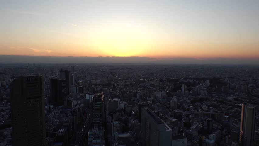 TOKYO, JAPAN : Aerial high angle sunrise CITYSCAPE of TOKYO. View of rising sun and dramatic sky around Shibuya. Japanese urban city life and nature concept. Long time lapse video, night to morning.