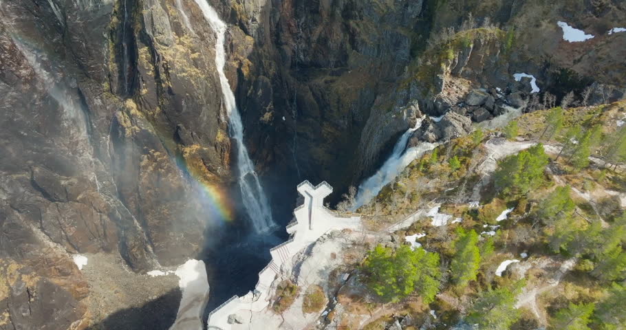 Viewpoint over Vøringsfossen canyon waterfall with rainbow reflection; drone