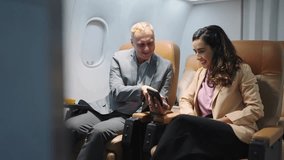 Passengers caucasian businessman using smartphone and talking with latin women colleague on seat in airplane while traveling by plane. Business trip, Business and travel - Powered by Shutterstock - Get 15% off with code: PIKWIZARD15