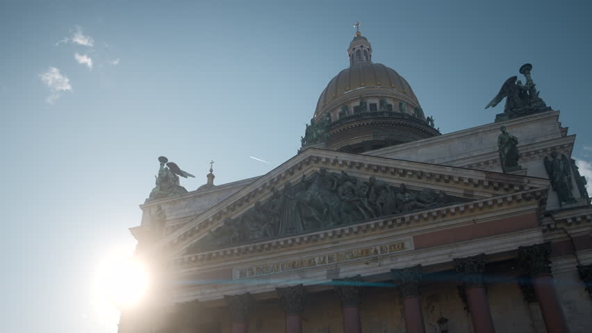 View from below of ancient cathedral with statues and dome. Action. Beautiful old cathedral on background of bright sun and blue sky. Dome and statues in architecture of ancient cathedral | Shutterstock HD Video #1104433135