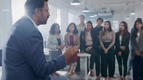 A middle aged Indian Asian confident male entrepreneur or businessman is communicating or discussing with his team members or employees during a group meeting in a modern corporate start up office - Powered by Shutterstock - Get 15% off with code: PIKWIZARD15