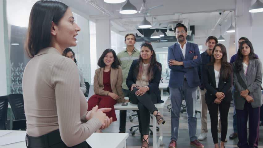 A young Indian Asian female confident entrepreneur or businesswoman passing on a project brief or communicating in a group meeting with employees or team members in a modern corporate office start up | Shutterstock HD Video #1104433635