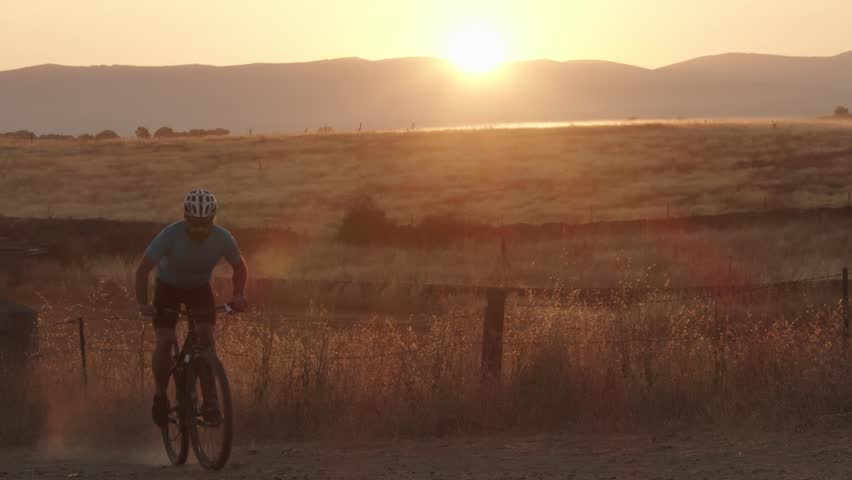Male mountain biker pedaling during a sunrise in nature. Mountain biking concept